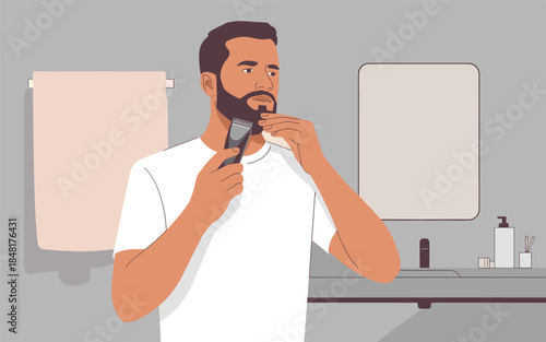 Man shaving in a bathroom with a razor, standing in front of a mirror and countertop with grooming products