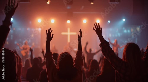 Worshipers with hands raised during a contemporary christian church service with cross