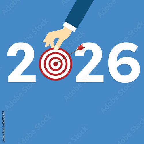 Human hand holding business target for a business year 2026. Red arrow hits center. 	
