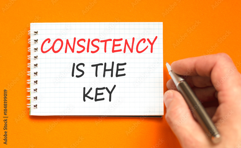 Fototapeta premium Consistency is the key symbol. Concept words Consistency is the key on beautiful white note. Beautiful orange background. Businessman's hand. Business consistency is the key concept. Copy space.