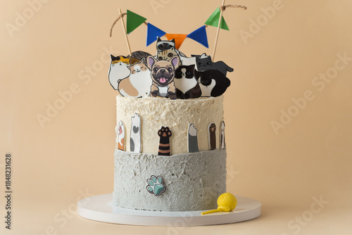 Beautiful big birthday cake decorated with edible dogs and cats figurines on the beige background. Cake for a little dog and cat lover