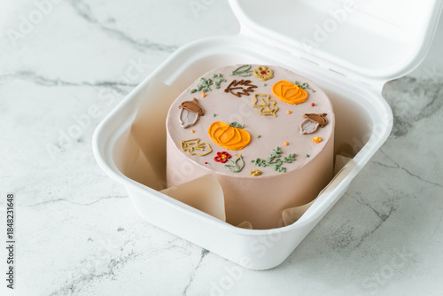 Autumn themed and Halloween festive bento cake in a gift box on the white marble background