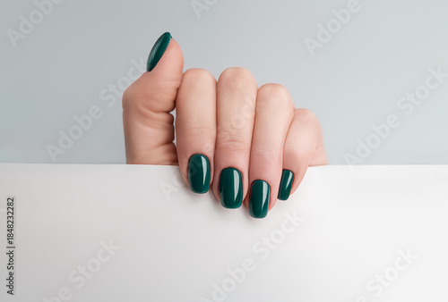 Manicured female hand holding blank white paper with copy space, minimal studio mockup