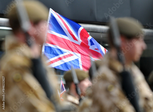 Soldiers march past a Union Flag. 