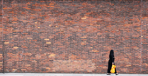 Fotografía A woman walks past a very large wall.