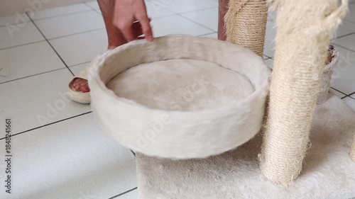 A man disassembles a cat's house, unscrewing the round bed.