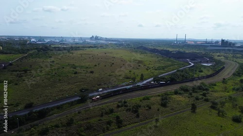 Camera panning from coal heaps and coal trains to Richards Bay Industrial Export harbour South Africa 4K Aerial Video.