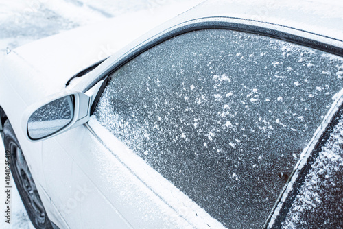 Winter frozen car window, texture freezing ice glass background. Front view. Frozen car covered snow at winter day, view front window windshield and hood on snowy background. happy new year.