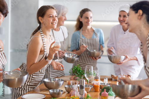 Fotografía Young woman drinks wine and talks to group during cooking master class