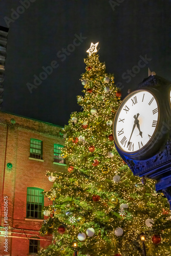 A magical holiday evening in Toronto's Distillery District, illuminated by festive lights and featuring a grand Christmas tree beside a vintage clock.