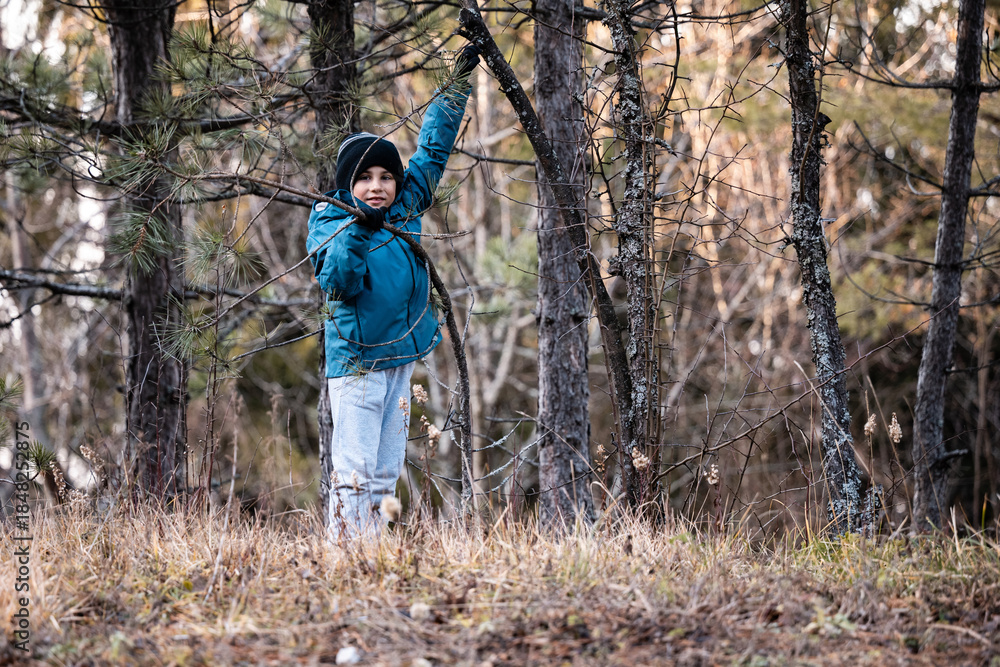 Naklejka premium Young boy exploring forest in warm clothes