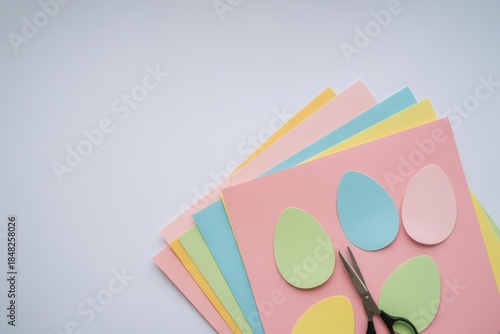 Pastel Easter Paper Craft Flat Lay — Cut-Out Egg Shapes on Stacked Pink, Blue, Yellow & Green Sheets with Scissors, Minimal Gray Background, Copy Space, DIY Kids Activity