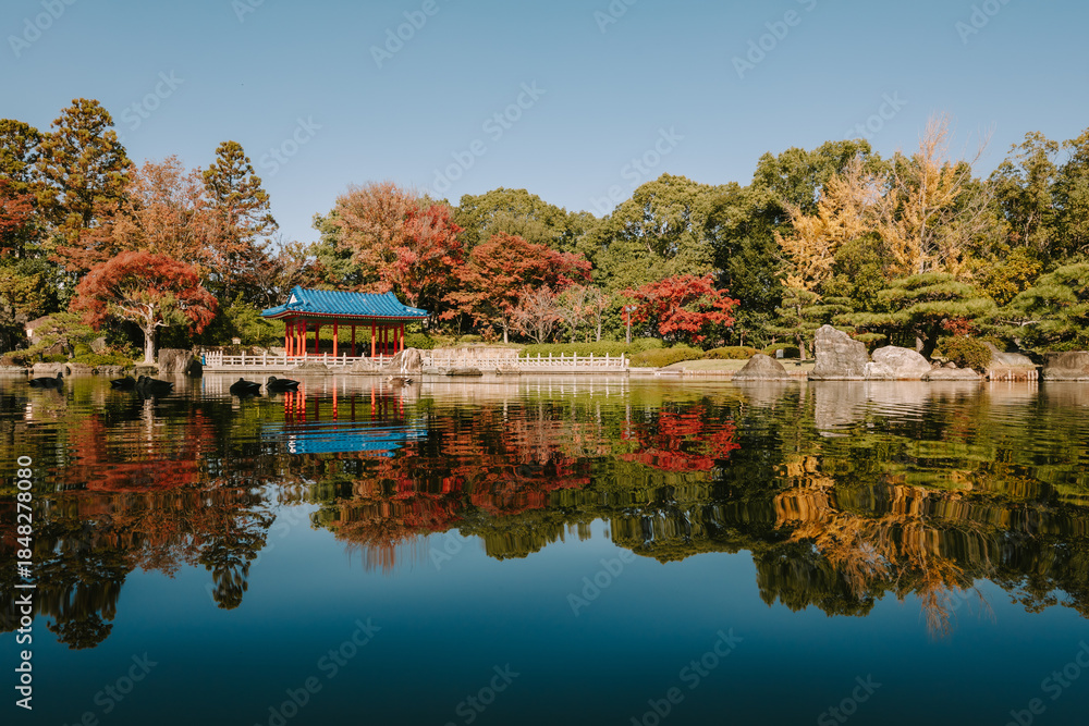 Obraz premium Wide Panoramic View of a Traditional Japanese Pavilion Reflected in a Still Garden Pond