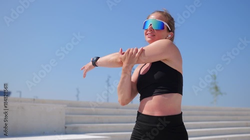 Woman with sunglasses performs a stretch on steps
