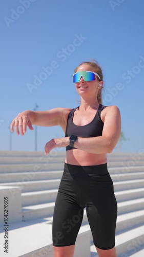 Woman stretching outdoors near water under clear sky