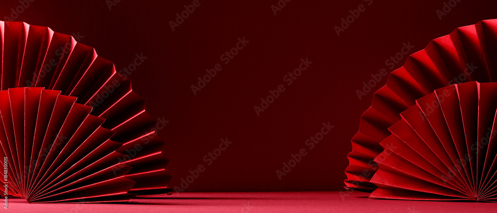 Naklejka premium Elegant oriental red paper fans on a red surface, traditional lunar new year festive background.