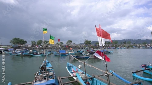 Fishing boats anchored at Pangandaran Harbor in the morning with a cloudy sky as a background.