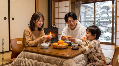 コタツでミカンを食べる笑顔の家族