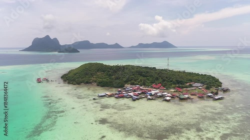 Aerial view of sea  village over clear turquoise waters in Selakan Island Semporna, Sabah, Malaysia. Scenic seascape with coral reefs, coastal village, and blue tropical sky.