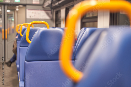 Close-up of empty train seats with blue upholstery and orange handles in modern public transit.