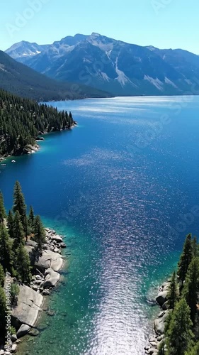 High-angle view of a sparkling blue mountain lake with a pine-lined inlet