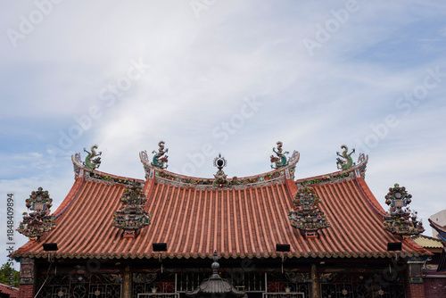 Ornate roof detail of Penang Kuan Yin Temple, featuring traditional Chinese architecture with dragon carvings and decorative ceramic ornaments under a clear sky.