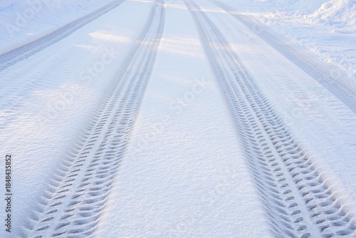 Tire tracks deeply pressed into fresh snow on a bright winter day