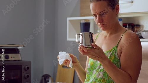 Woman Inspecting Small Metal Pitcher with Tissue in Hand in Soft Side Light as She Prepares for Pouring Wax, Handmade Candle Concept