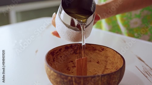 Melted Wax Stream Pouring Directly into Coconut Shell with Wooden Wick in Clear Close Up Angle, Handmade Candle Concept