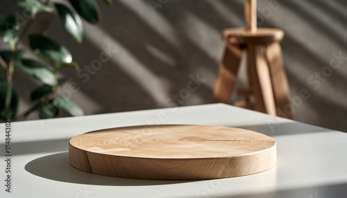 Modern wooden lazy Susan on white table with green plant