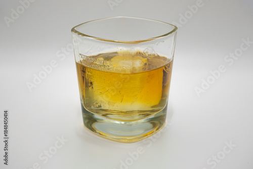 Close-up of a glass of whiskey with ice, isolated on a white background. Concept of alcohol drink, bar, relaxation, evening drink, and luxury lifestyle