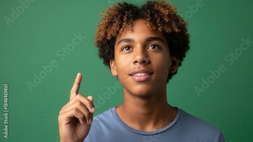 Portrait of a smiling young person with curly hair against vibrant green background