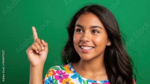 Portrait of a smiling young woman with long dark hair and vibrant floral dress against a green