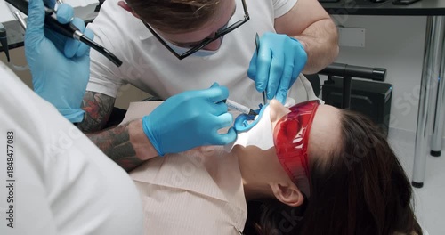Dentist making tooth cleaning for patient in dental modern clinic. Oral hygiene and prophylactic cleaning. Female patient at hygiene teeth cleaning procedure in dentistry. Teeth Cleaning.