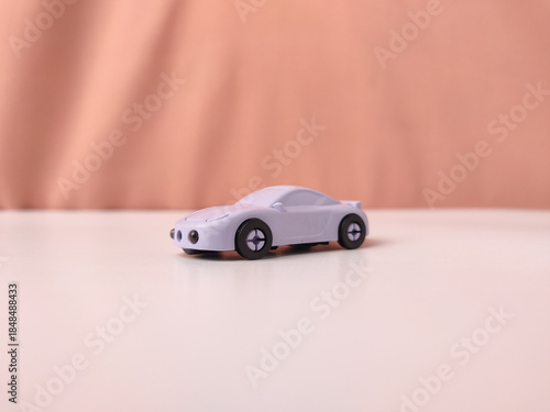 The image is of a purple toy car on a table with brown background