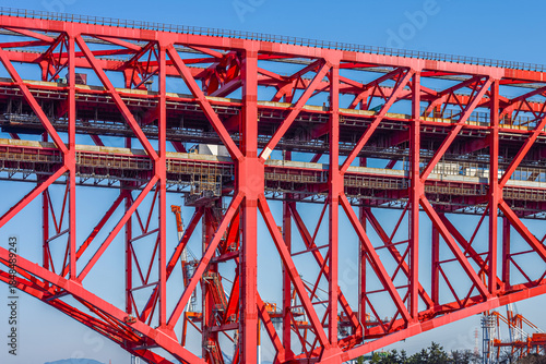 Massive Red Steel Truss Cantilever Minato Bridge Structure under Clear Blue Sky. Detail of the red steel truss structure of the Minato Bridge in Osaka, Japan. Showcasing engineering and infrastructure
