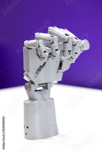 Mechanical plastic robot hand on purple and white background