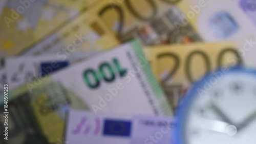 Time on a clock with euro banknotes in the background highlights the connection between time and money