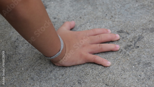 Close-Up of a Child's Hand on a Concrete Surface with a Focus on Textural Details