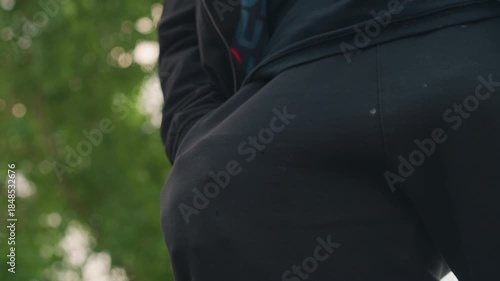 courier halts beneath shaded leafy surroundings, messenger pauses momentarily near entrance under leafy branches, parcel carrier takes short break at gate beneath canopy of green leaves