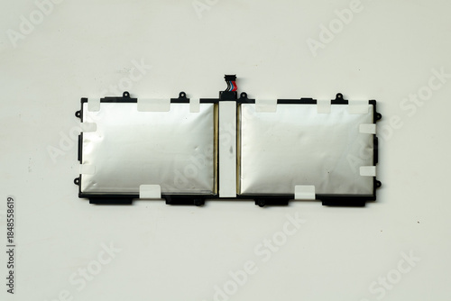 A pair of severely swollen silver lithium polymer battery cells for a laptop or tablet, removed from the device and shown isolated against a plain white background.