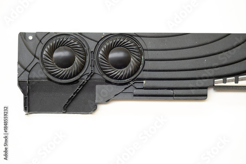 lose-up technical shot of a laptop internal stereo speaker module featuring dual circular drivers with integrated protective grilles and structural black plastic housing.