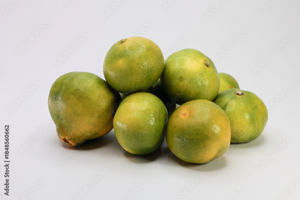 Obraz premium A Group Of Greenish Yellow Citrus Fruits, Possibly Unripe Mandarins or Limes. The Image Highlights The Natural Color Gradient And Freshness Of The Harvest.