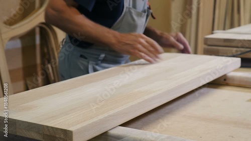 man putting boards from conveyor belt into wood finishing machine while working at furniture factory. Industrial manufacturing process. Woodworking production. Carpentry, creative industry and person