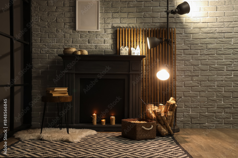 Fototapeta premium Interior of living room with glowing lamp, coffee table and firewood near fireplace in evening