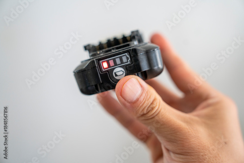 Hand holding camera battery with low charge indicator light