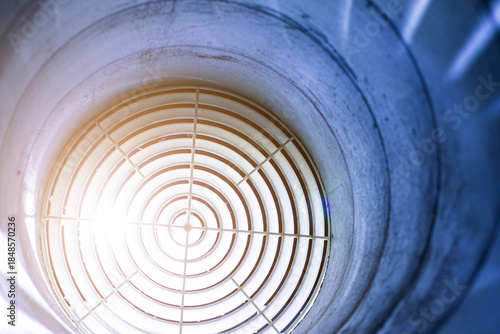 A close-up, architectural shot of a circular air vent on a white ceiling, showing concentric circles leading to a central point. The design highlights ventilation and climate control systems.