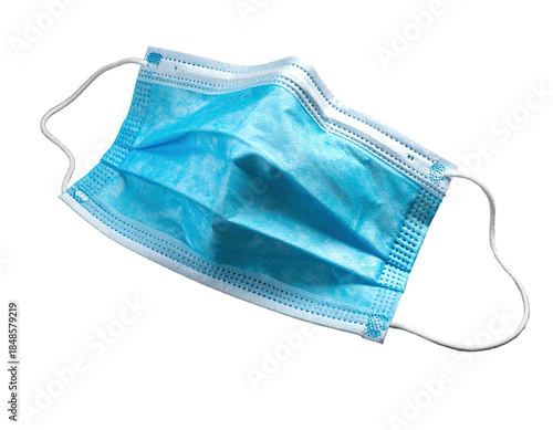 A blue, pleated surgical mask with white ear loops against black