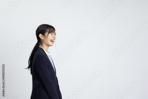 Side Profile of Smiling Young Businesswoman in Front of White Wall