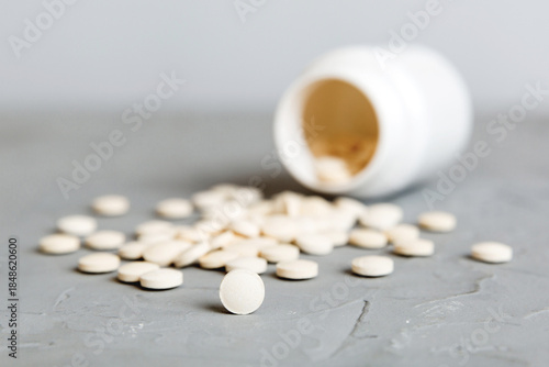 Slika na platnu Medicine bottle and white pills spilled on a light background